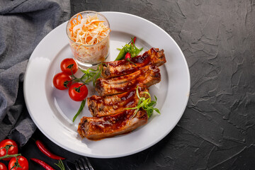 grilled ribs in barbecue sauce with cabbage salad and cherry tomatoes in white plate