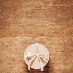 Gift in wooden box with light cream ribbon bow on oak table