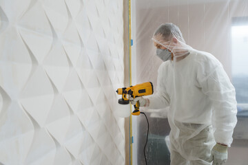 The painter is painting a 3d wall with a spray gun. - obrazy, fototapety, plakaty