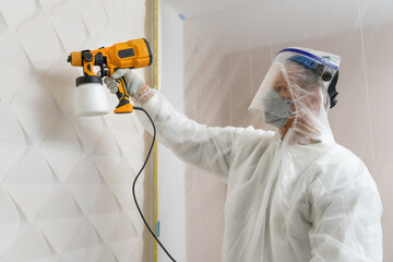 The painter is painting a 3d wall with a spray gun.