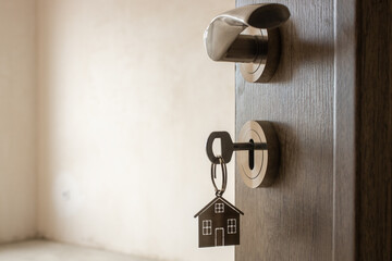 Open door to a new home. Door handle with key and home shaped keychain. Mortgage, investment, real...