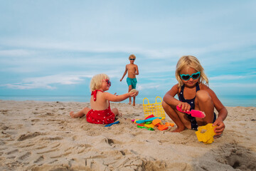 kids play with sand on beach vacation, boy and girls building sand castle