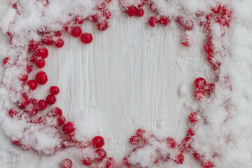 Frozen red currant berries in the snow on a white wooden background. copy space.