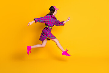 Fototapeta na wymiar Full length profile portrait of attractive lady running headwear magenta outfit isolated on yellow color background