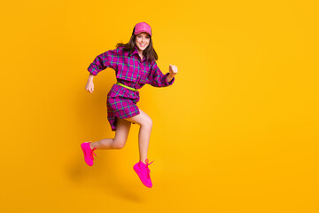Fototapeta na wymiar Full body portrait of attractive lady smile jump run headwear purple clothing isolated on yellow color background