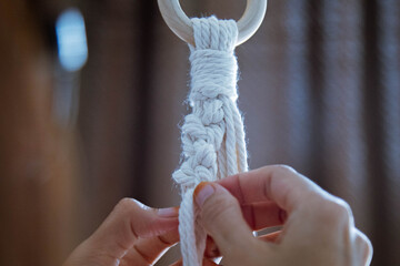 Close-up of a young woman hand tight the rope to making macrame