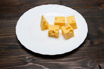 Several pieces of cheese with holes on a white plate