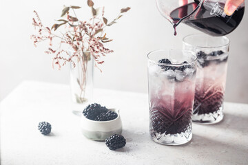 Fototapeta na wymiar Refreshing Blackberry Lemonade with ice in crystal glasses on white background
