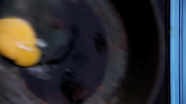 Overhead shot: putting an egg in an old pan over a cooking stove for camping, waiting until it starts to turn white.
