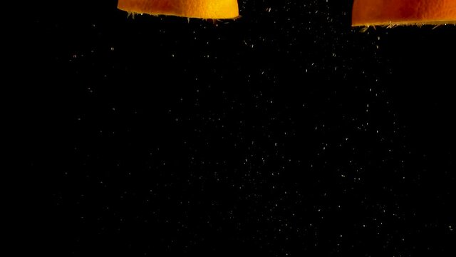 Orange halves falling, drop into water with air bubbles and a smooth black background. perfect for advertising or commercial videos for lemonade, juice and cocktails Also perfect for  baar and drinks