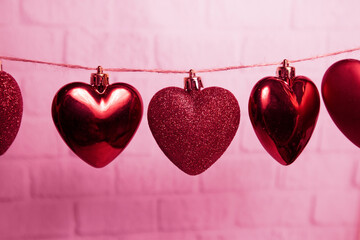 red hearts hang on a thread on a pink background