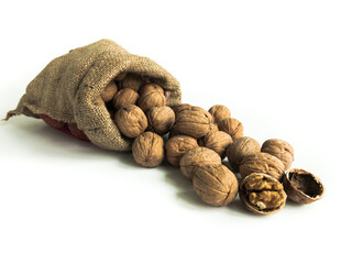 Heap of walnuts in sack bag with shell and kernel on an isolated white background with copy space. Front view.