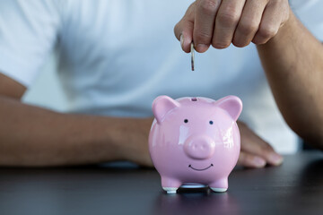 Savings and finance concept. man hand putting money coin in piggy bank for saving money and plan finance.Save the money,