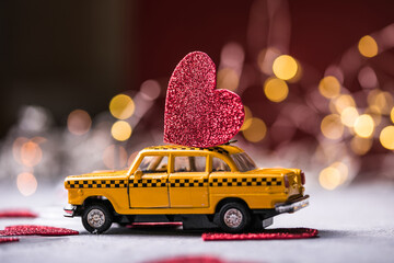 Red heart on toy yellow  taxi car on red background. Travel love concept with copy space.