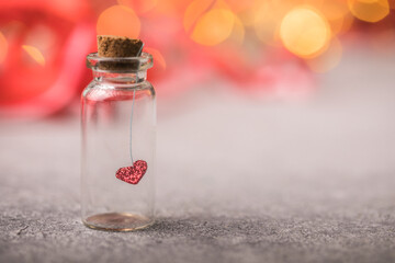 Glass jar and red heart on red background. Concept of love in Valentine's Day.