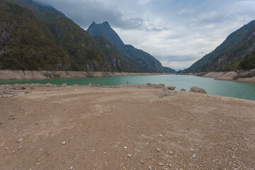 Unrecognizable lonely person on the dry shore of Lake Mis, Dolomiti Bellunesi National Park, Dolomites, Italy