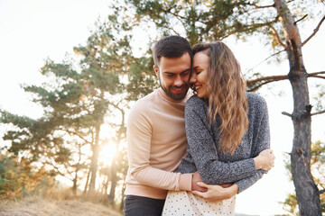 Embraces each other. Cheerful lovely young couple having a rest outdoors together