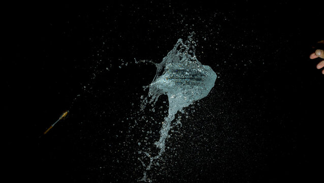 A High-speed Image Of A Thrown Dart Hitting A Water Balloon, And Popping It.