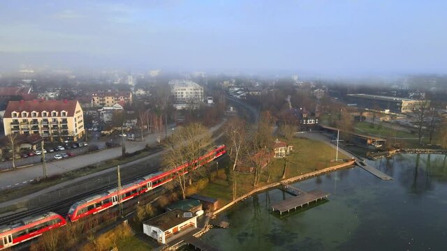 A train passes through the town of Starnberg, near Munich, during the morning. Aerial view of a drone tracking the train.