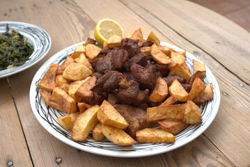 grilled pork with french fries and salad on a wooden table