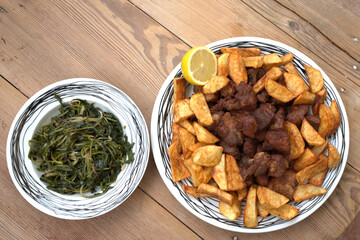 grilled pork with french fries and salad on a wooden table
