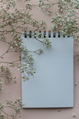 Notepad for notes and white flowers on a light background, top view