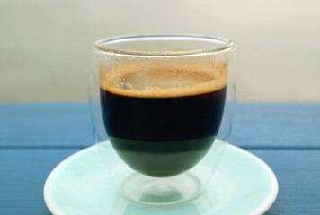 Glass of hot black coffee isolated on blue wooden table	