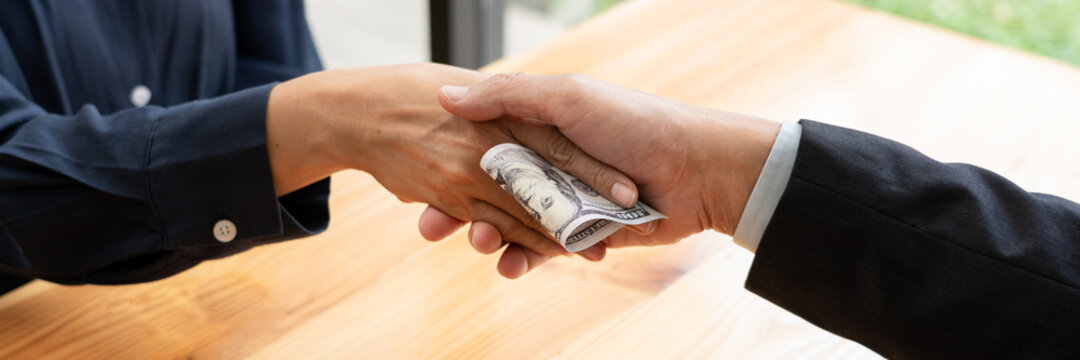 Businessman reciving money United States Dollars bills to corruption from his partner in business at working desk - bribery concept.