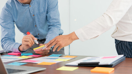 Creative group of business people brainstorming use sticky notes picking to share idea on table decision Choosing Concept for developing plan in business conference room.