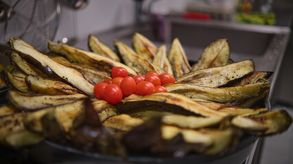 baked eggplants in long and delicious chunks accompanied by cherry tomatoes with close-up focus