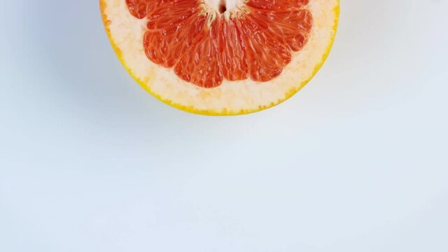 One half of a grapefruit rotates, close up. Space for text. The concept of a healthy lifestyle.