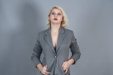 Attractive tall blonde girl in gray jacket, sexy portrait in studio