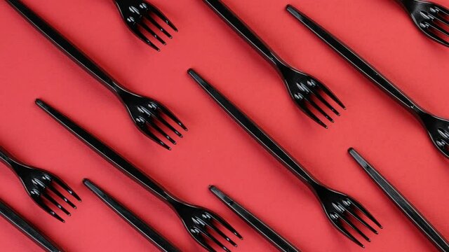 Eco concept. Plastic disposable forks stacked in rows on a red background rotate in a circle. Pattern