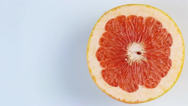 One half of a grapefruit rotates, close up. Space for text. The concept of a healthy lifestyle.