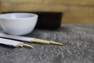 Wooden chopsticks, sushi sticks and saucepan with sauce. Selective focus