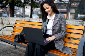 A young business woman communicates with a business partner via the Internet in a public park