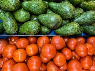 Green avocados and red tomatoes on the market. Netanya, Israel