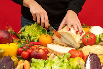 A girl cutting bread on a table with various types of vegetables