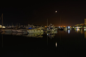 port in crescent moon night with reflections in the sea