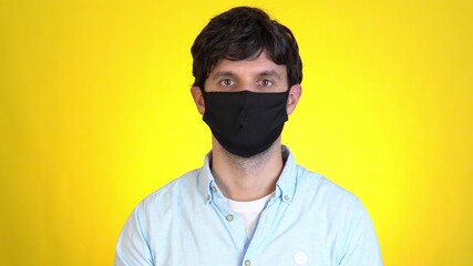 Man isolated on yellow background studio. Healthy lifestyle ill sick disease treatment cold season concept. Pointing index fingers on face mask showing thumbs up