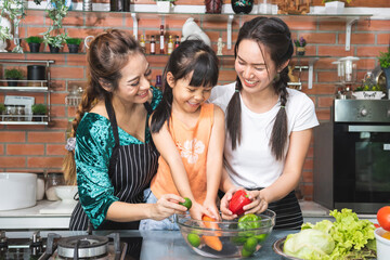 Happy loving family preparing food together. Smiling asian three girl washing fruits and vegetables and having fun in the kitchen. sister Healthy food