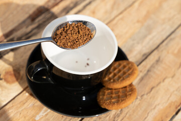 close up morning instant coffee with iron spoon and two biscuit cookies on a wooden table