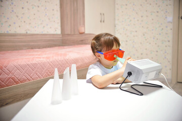 Fototapeta na wymiar the girl cleans her nose with the Antibacterial ultraviolet quartz lamp to prevent the body from bacteria and coronavirus pandemic viruses. Child health care.