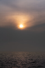 sun behind clouds or fog in the sea