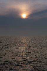 Fototapeta premium sun behind clouds or fog in the sea