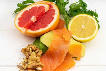 Salmon with grapefruit, lemon, and walnuts on a white wooden table