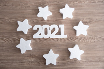 White 2021 new year number and stars on wooden background