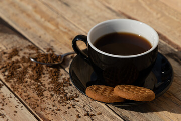 close up morning instant coffee with iron spoon and two biscuit cookies on a wooden table