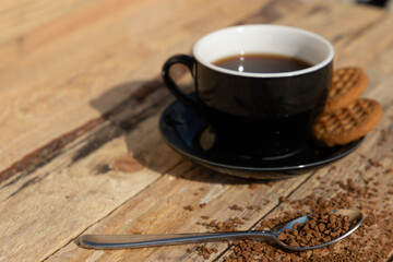 close up morning instant coffee with iron spoon and two biscuit cookies on a wooden table