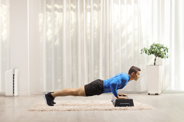 Man doing plank exercise on a step aerobic inside a room